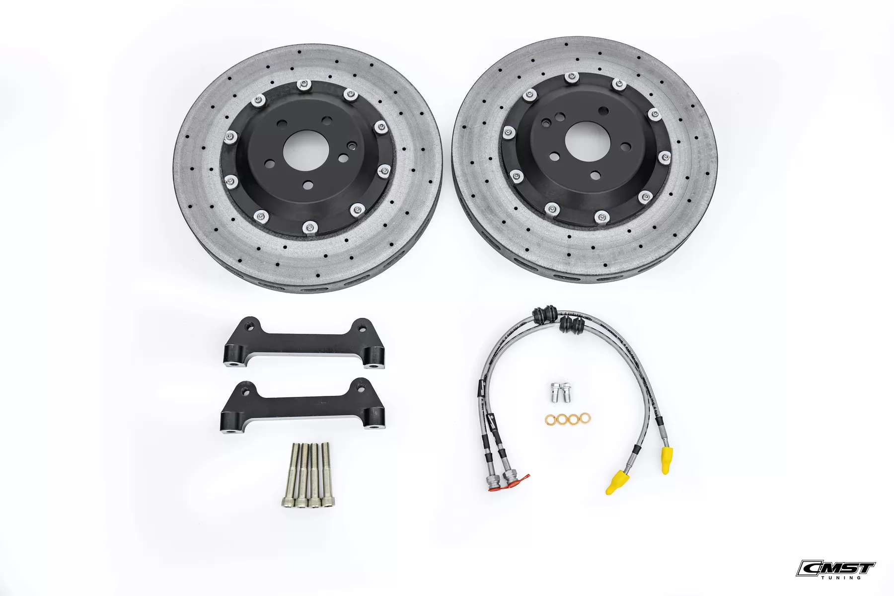 A complete CMST carbon-ceramic brake kit laid out: two discs, caliper brackets, bolts and braided lines